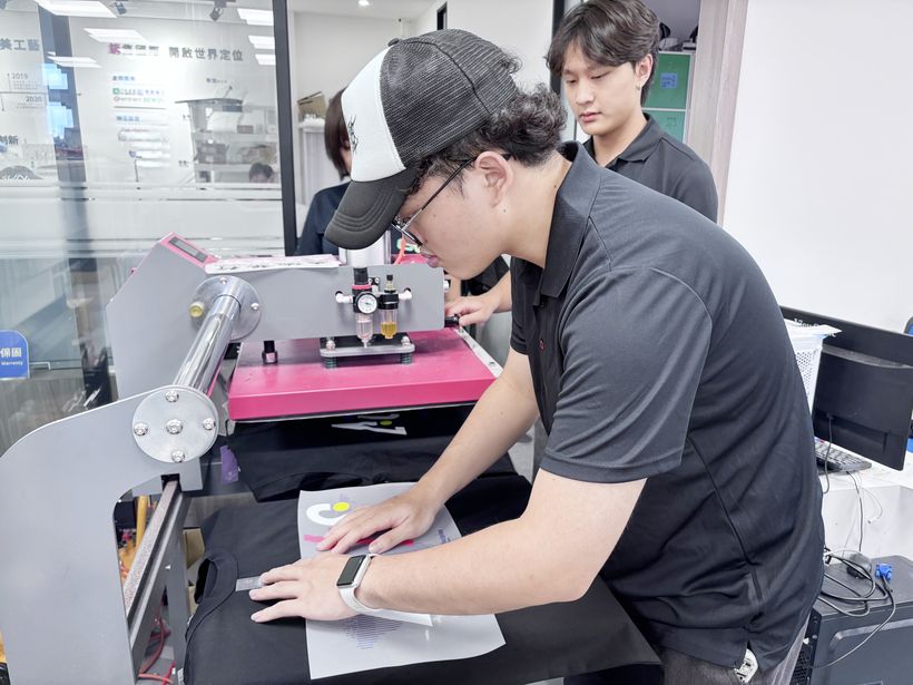 實習生依客戶需求對位,將圖樣燙印於衣服